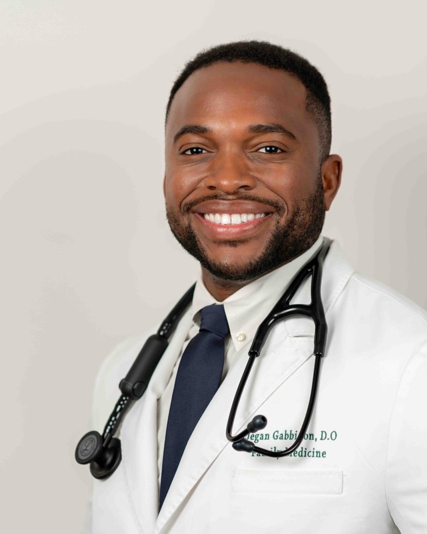 Official portrait of Dr. Jegan Gabbidon, D.O., founder and medical director of GreenTree Family Medicine, in a white embroidered coat with stethoscope